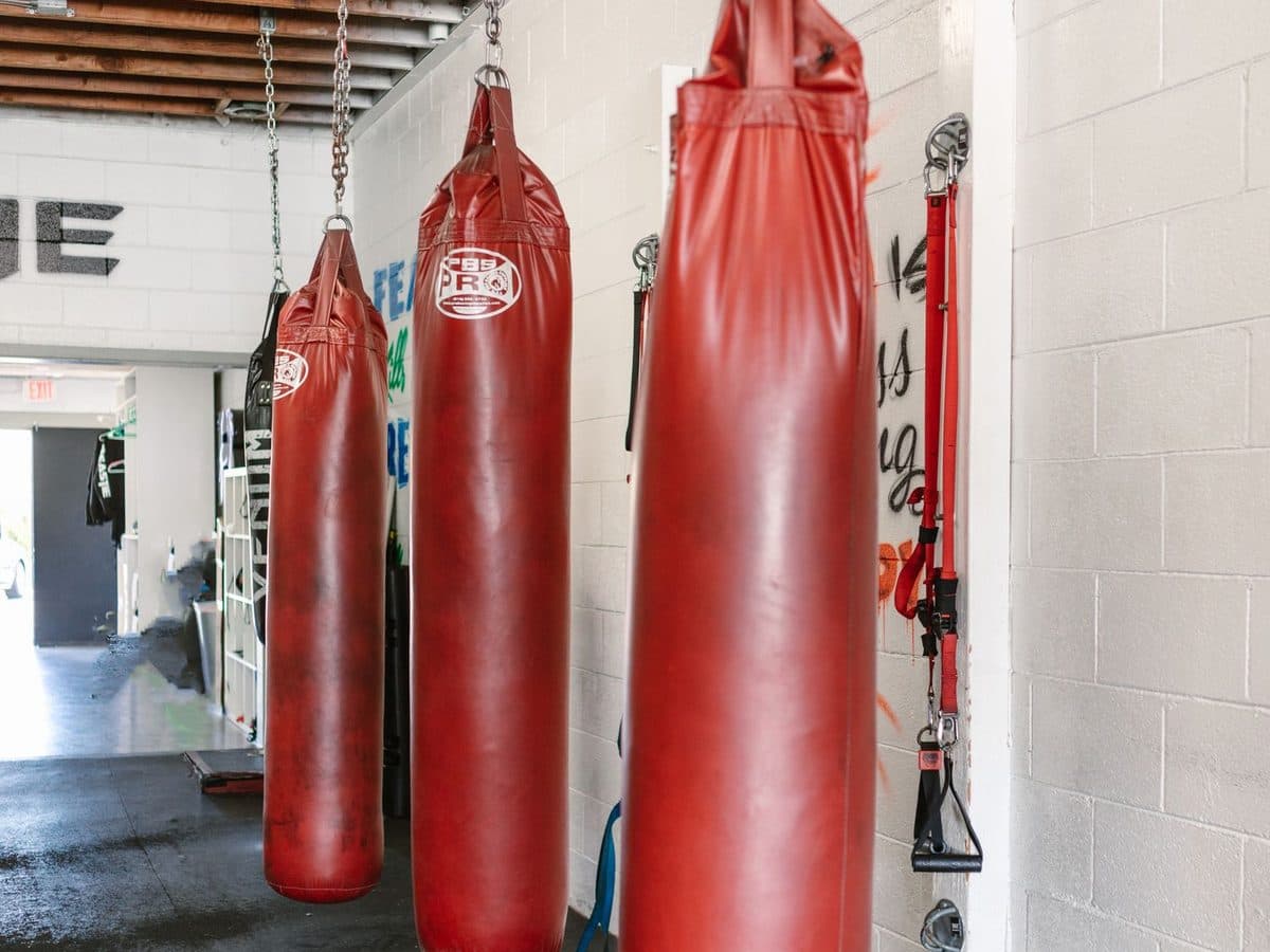 Row of red heavy punching bags hanging in a clean martial arts gym interior