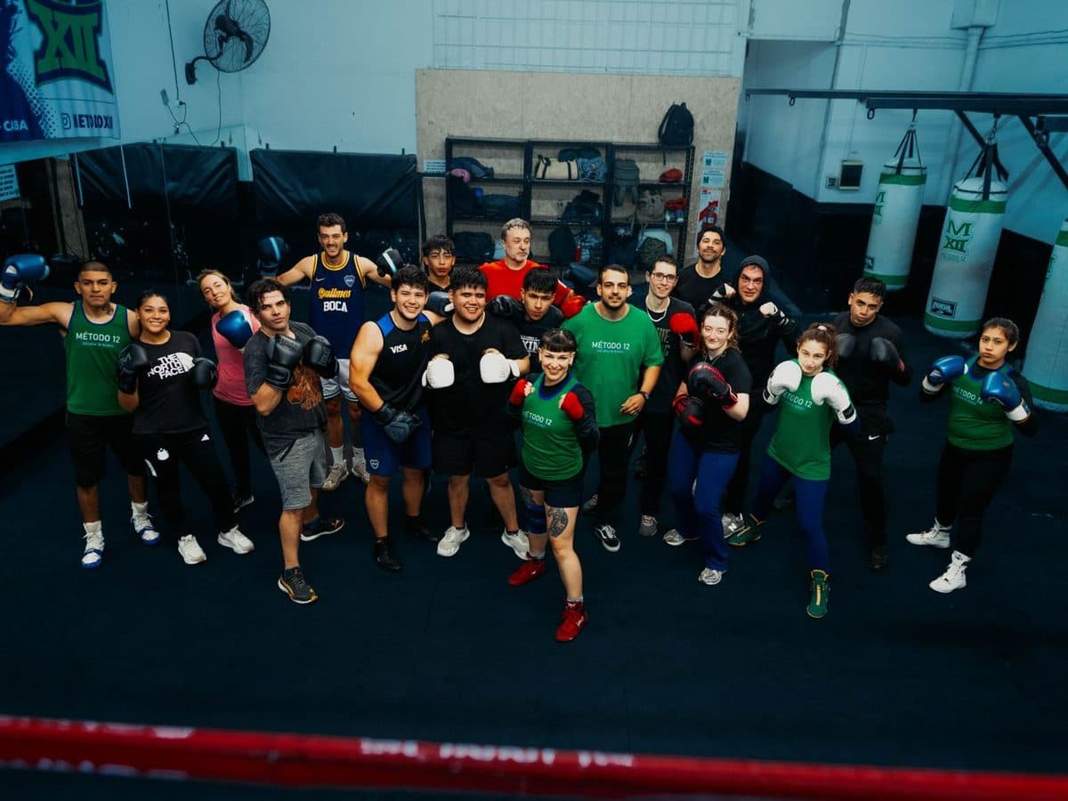 A full boxing class of members in gloves gathered together at a martial arts gym