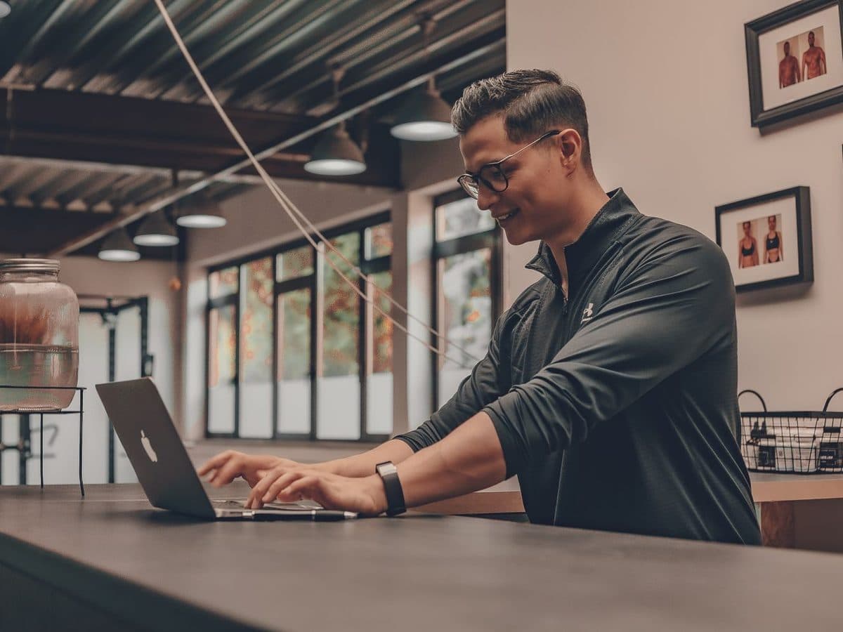 Calm martial arts gym owner working at the reception counter on a laptop, handling the day-to-day